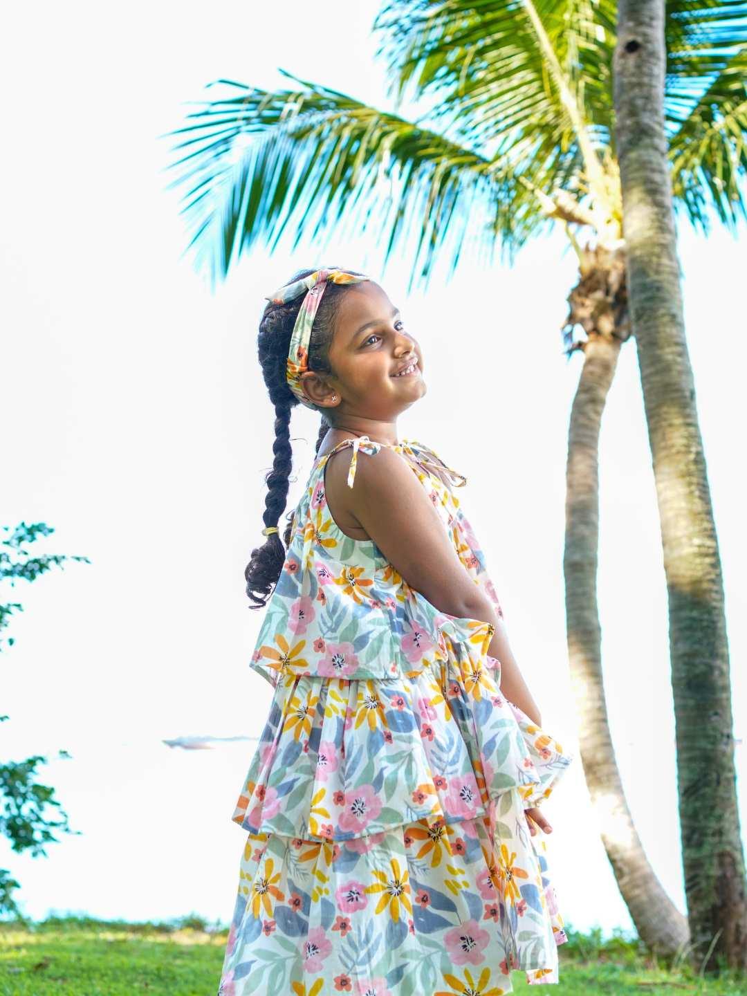 Girls tiered cotton dress in spring floral print with ruffled sleeves, made from sustainable fabric, perfect for casual wear.