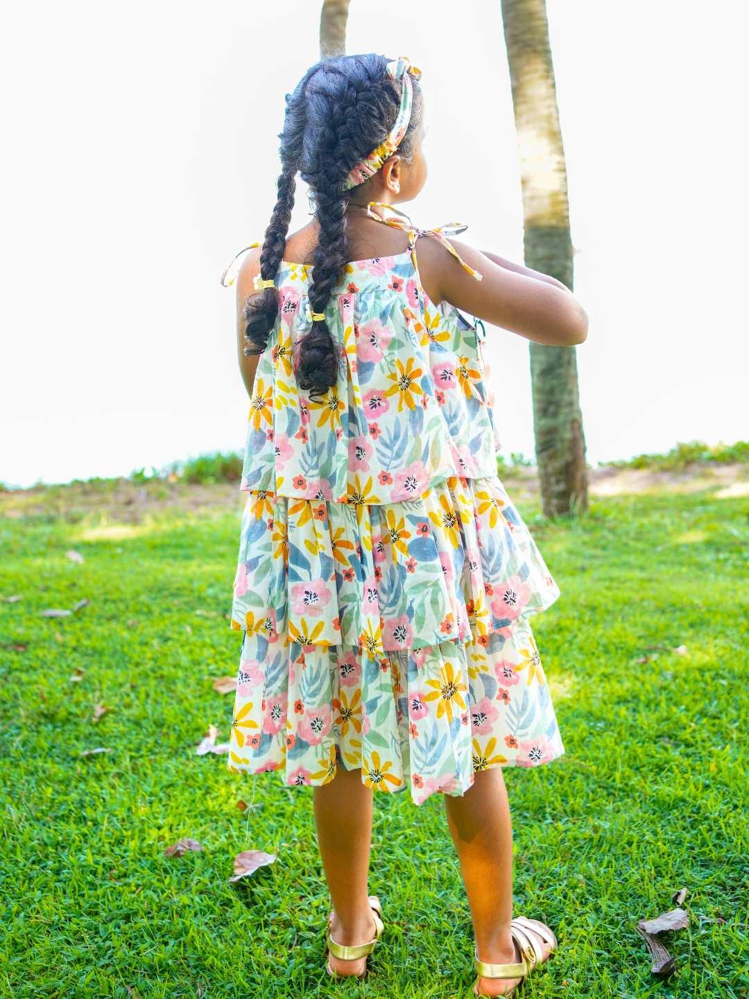Girls tiered summer dress in vibrant spring floral print, lightweight sustainable cotton fabric, casual style.