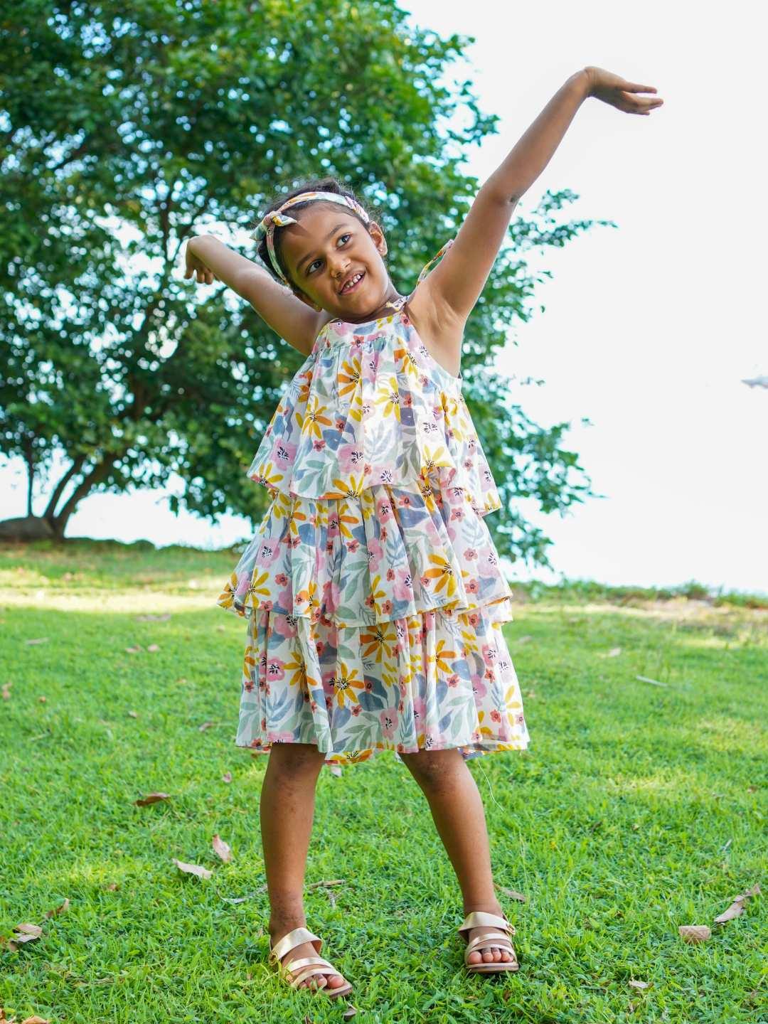 Girls cotton tiered dress in spring floral print with ruffled layers, sleeveless and knee-length, sustainable fabric.