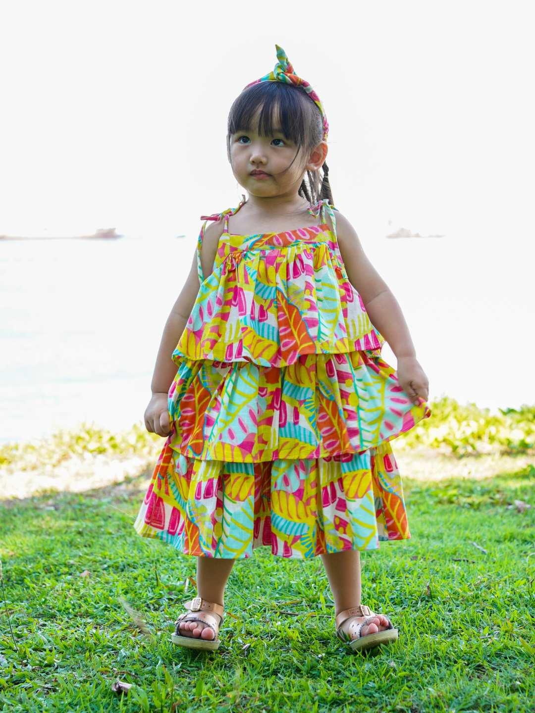Girls tiered sundress in bright sunset print, lightweight sustainable cotton, sleeveless with ruffle layers, toddler size.