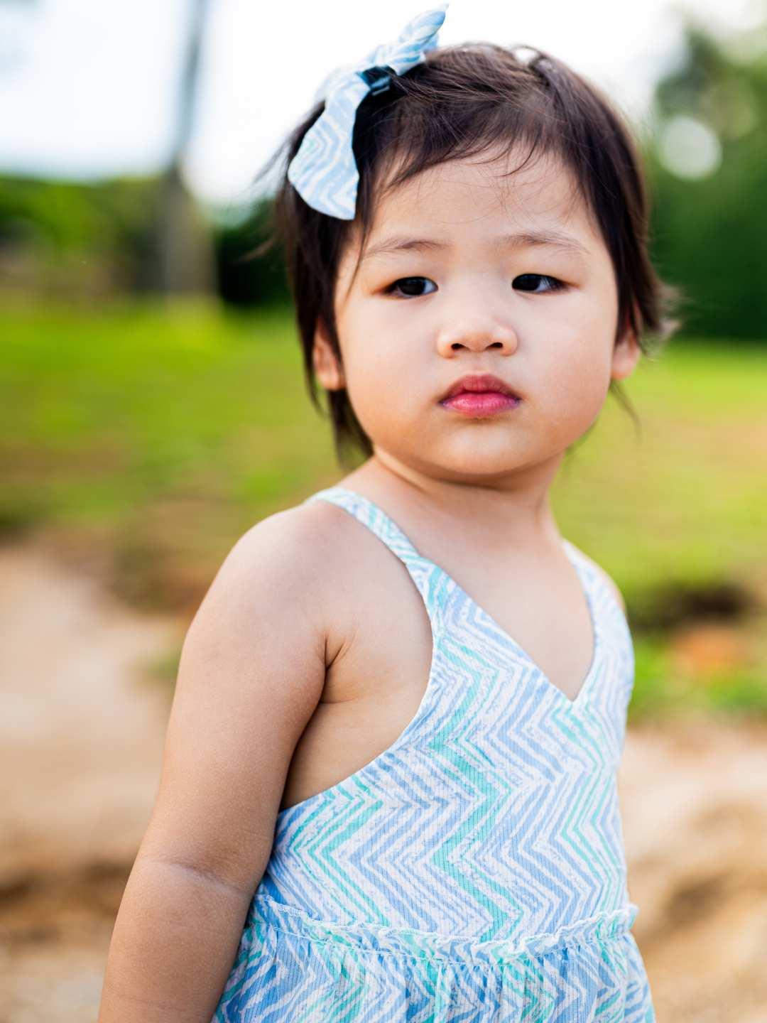 Toddler girl wearing an azure cotton dress with a chevron wave pattern, thin straps, and sustainable fabric.